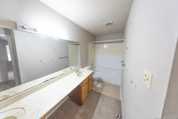 a bathroom with a granite countertop sink a mirror and a bathtub