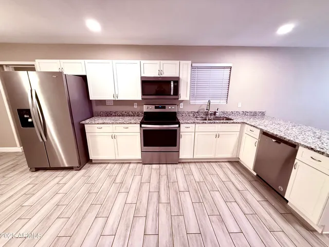 a kitchen with stainless steel appliances granite countertop a refrigerator a stove a sink and a microwave