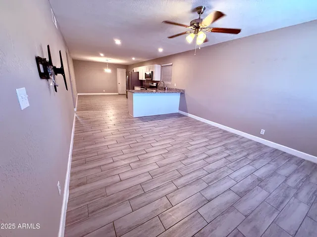 a view of an empty room with a window and wooden floor