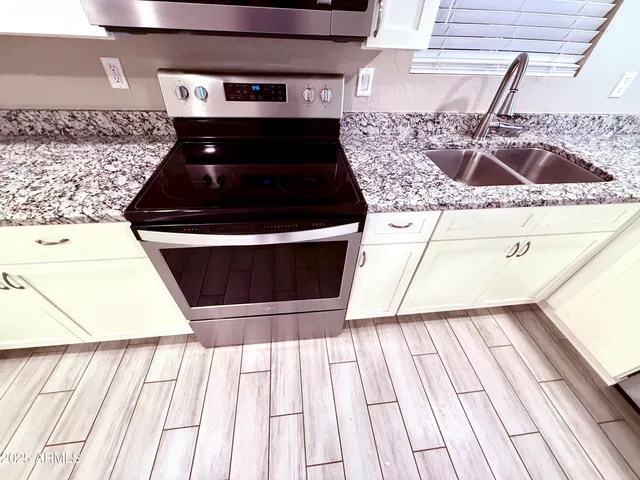 a kitchen with a stove a sink and white cabinets