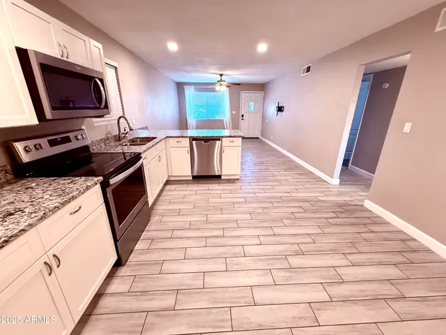 a large kitchen with stainless steel appliances granite countertop a stove a sink and a microwave