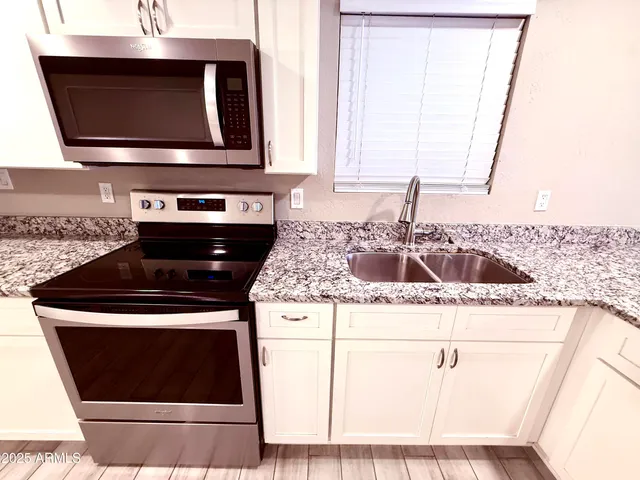 a kitchen with granite countertop a stove and a microwave