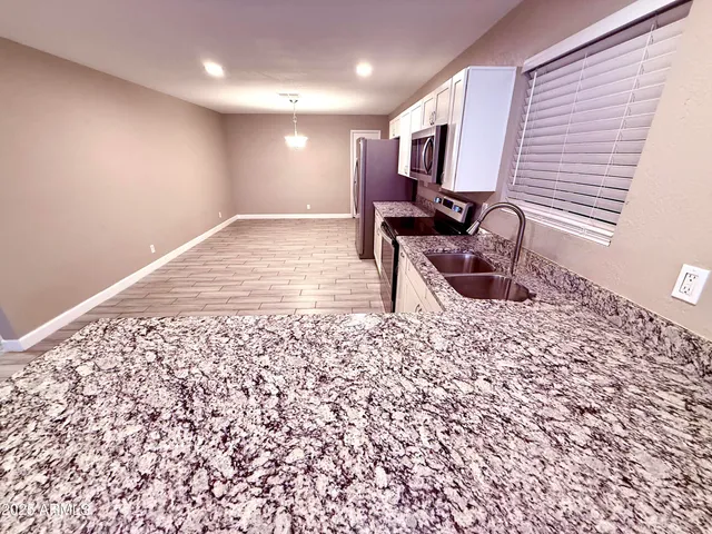 a view of a kitchen with kitchen island granite countertop a sink and a stove top oven