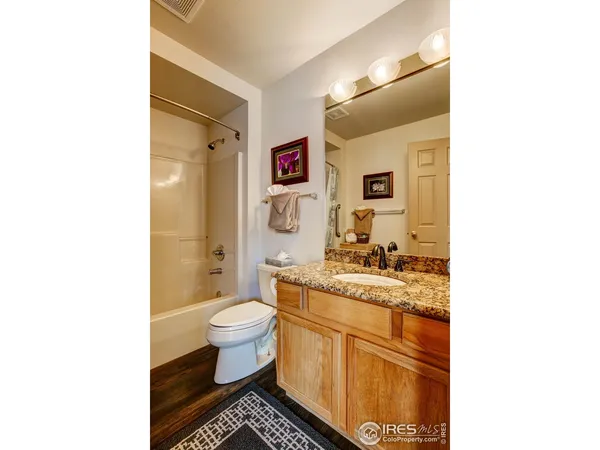 a bathroom with a granite countertop toilet sink and mirror