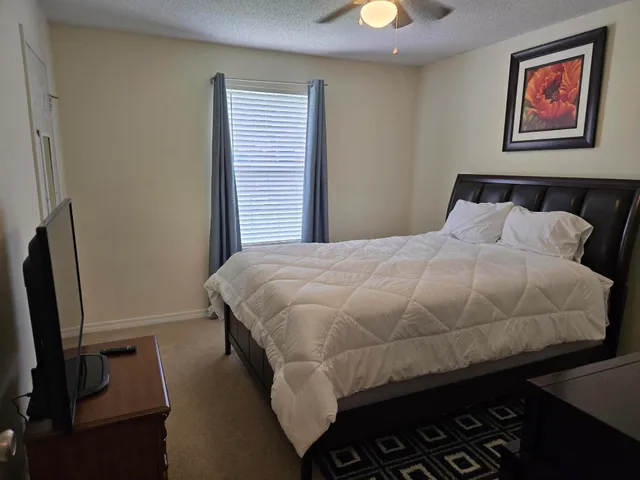 a bedroom with a bed and a flat tv screen on a dresser
