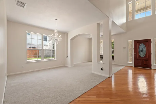 an empty room with chandelier fan and windows