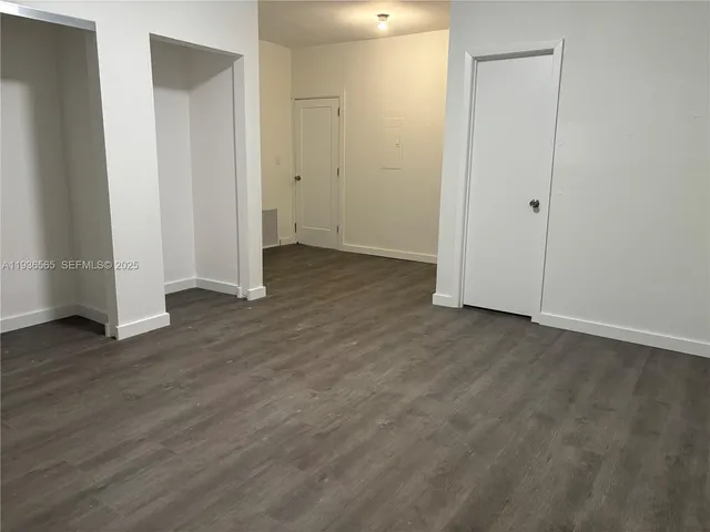 an empty room with wooden floor & closet area