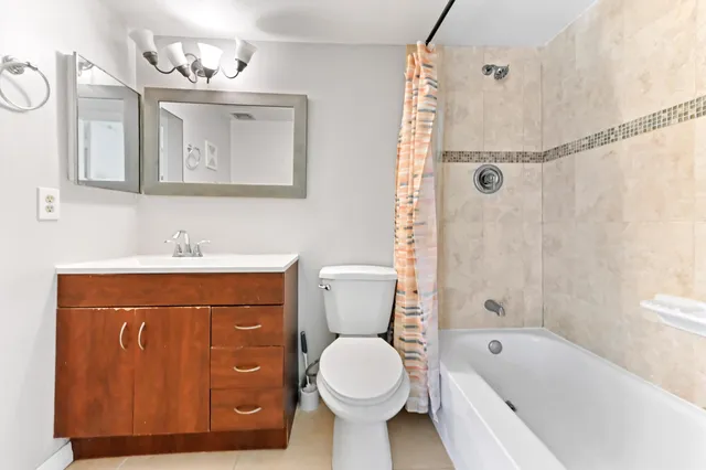 a bathroom with a toilet sink vanity tub and shower