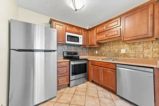 a kitchen with stainless steel appliances granite countertop a refrigerator stove top oven and sink