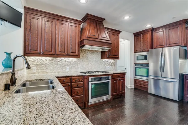 a kitchen with stainless steel appliances granite countertop a refrigerator stove and sink
