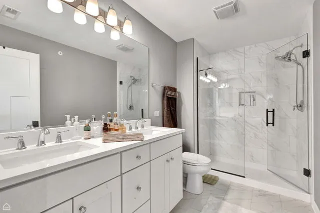 a bathroom with a double vanity sink toilet and shower
