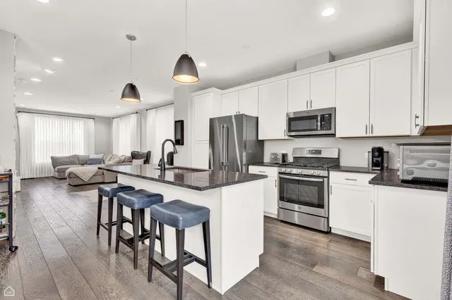 a kitchen with stainless steel appliances a stove a sink a microwave a center island and a refrigerator