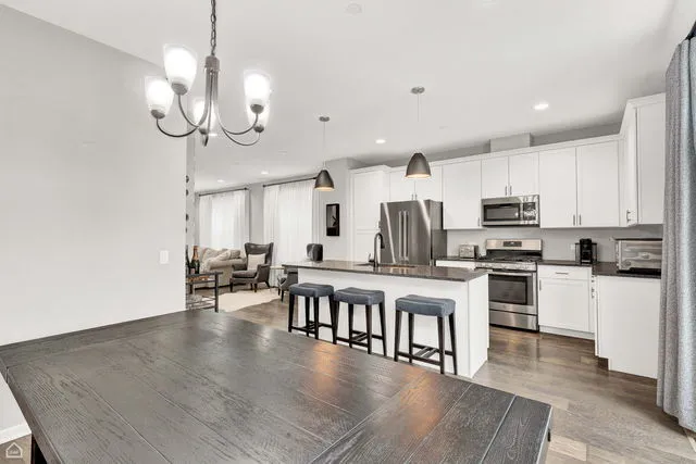a large kitchen with white cabinets stainless steel appliances and wooden floor