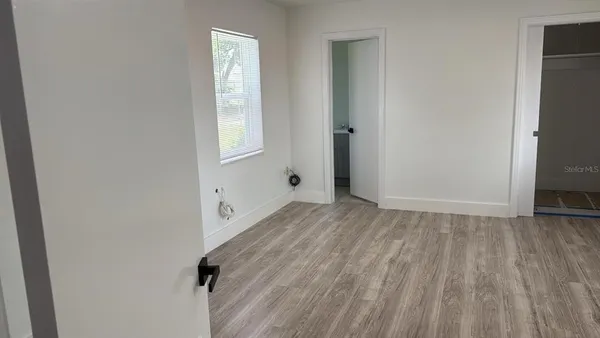 a view of an empty room with wooden floor and a window