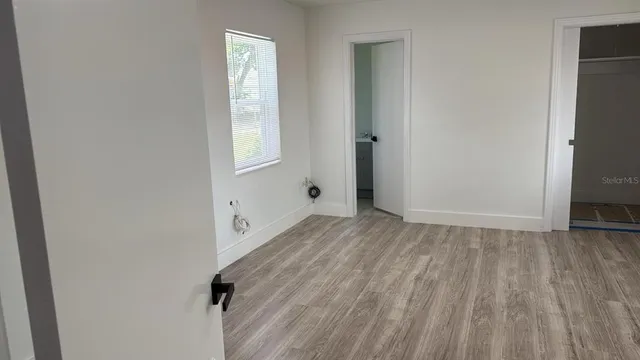a view of an empty room with wooden floor and a window