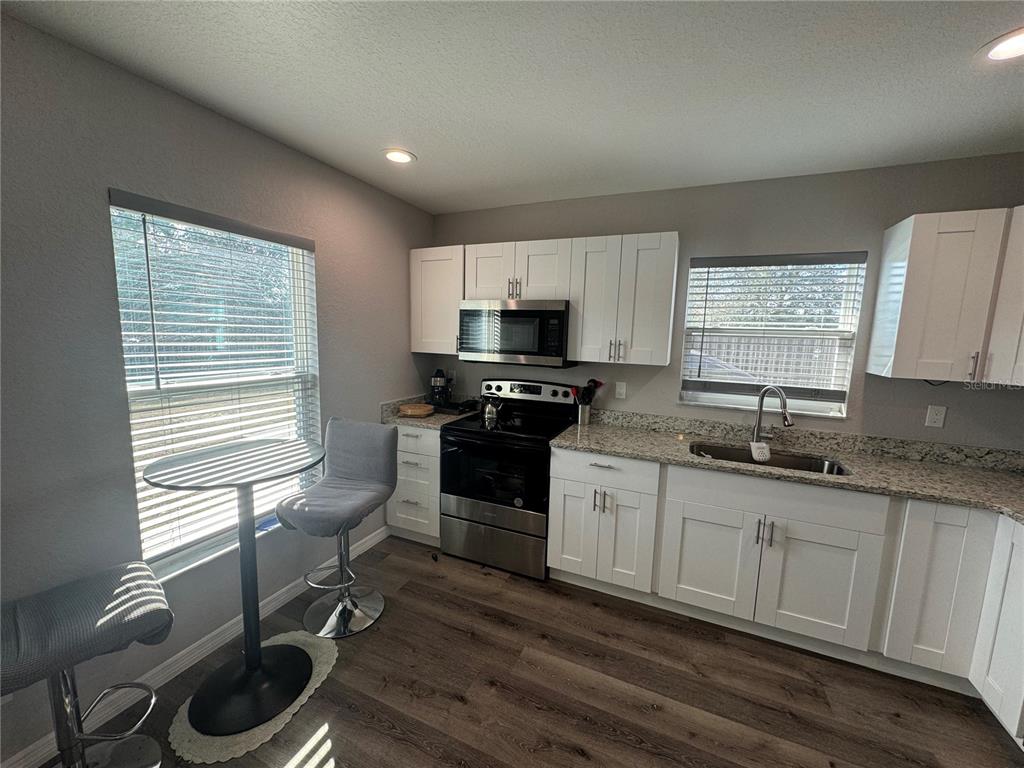 13183 Southwest 113th Place Dunnellon, FL 34432 - Photo 19 of 22 a kitchen with granite countertop a stove a sink and a microwave