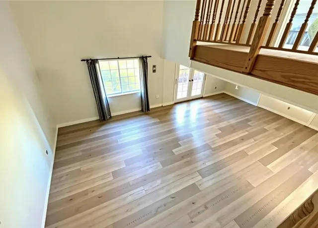 a view of an empty room with wooden floor and a window