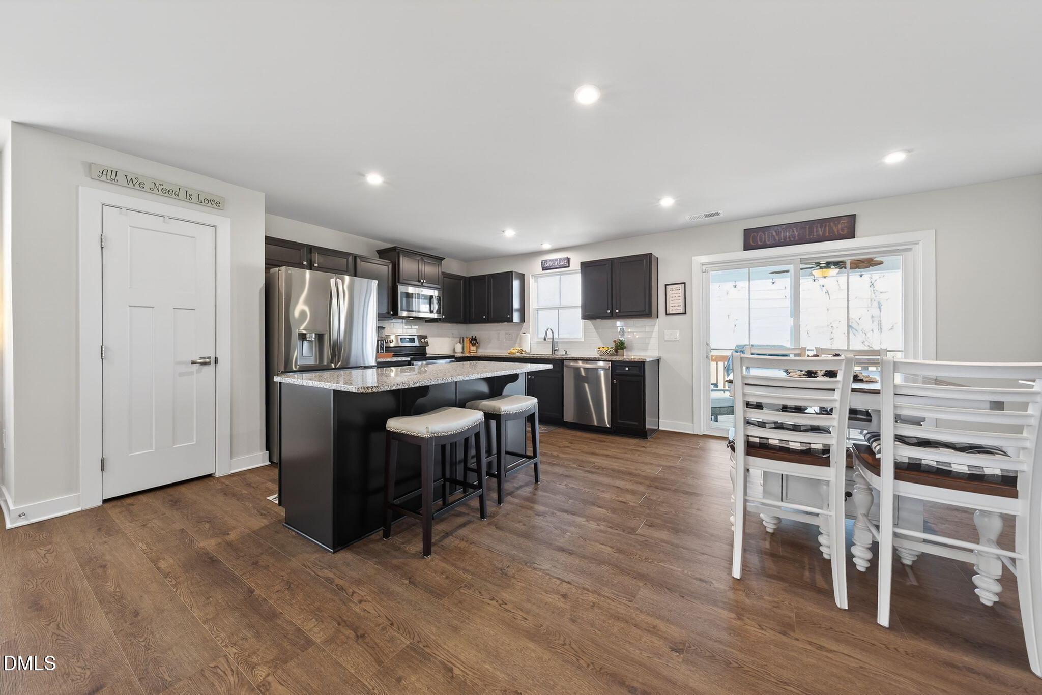 636 Jasmine Street Wendell, NC 27591 - Photo 9 of 30 a kitchen with stainless steel appliances kitchen island granite countertop a stove top oven a sink dishwasher and a dining table with wooden floor