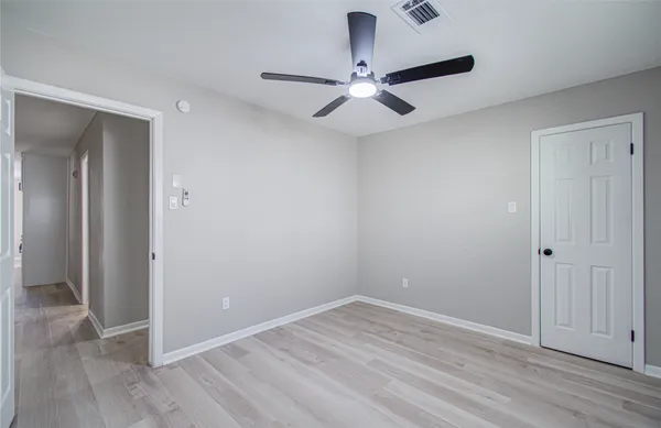 an empty room with wooden floor closet and fan