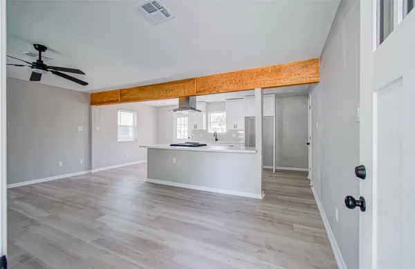 a view of a kitchen with kitchen island a sink wooden floor and a glass door shower