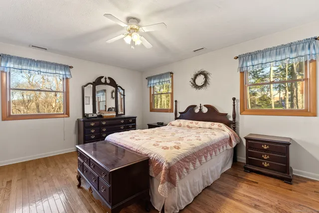 a bedroom with a bed and a dresser with wooden floor