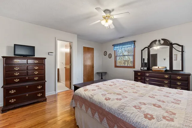 a bedroom with a bed a mirror on dresser and a flat screen tv