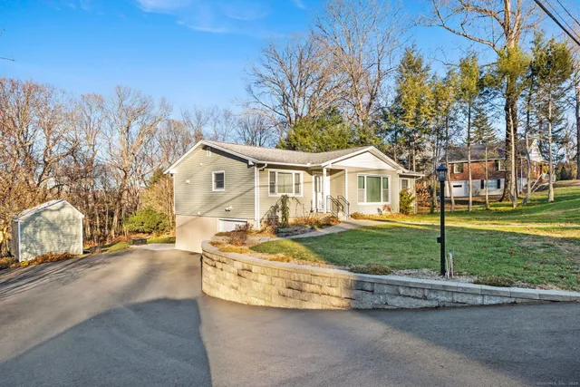 a front view of a house with a garden and tree