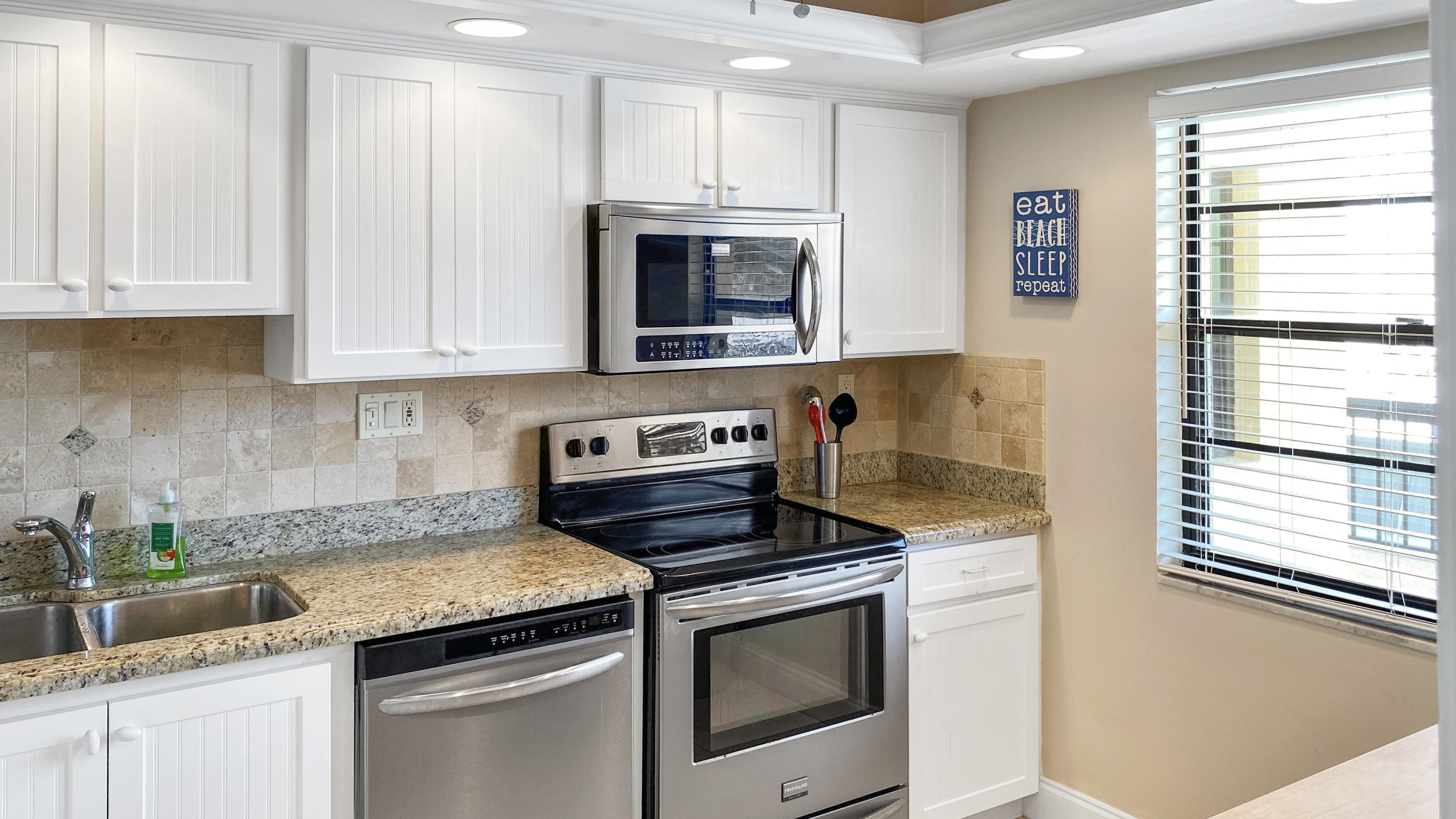 275 South Beach Road, Unit B202 Jupiter, FL 33469 - Photo 7 of 25 a kitchen with granite countertop white cabinets and white appliances