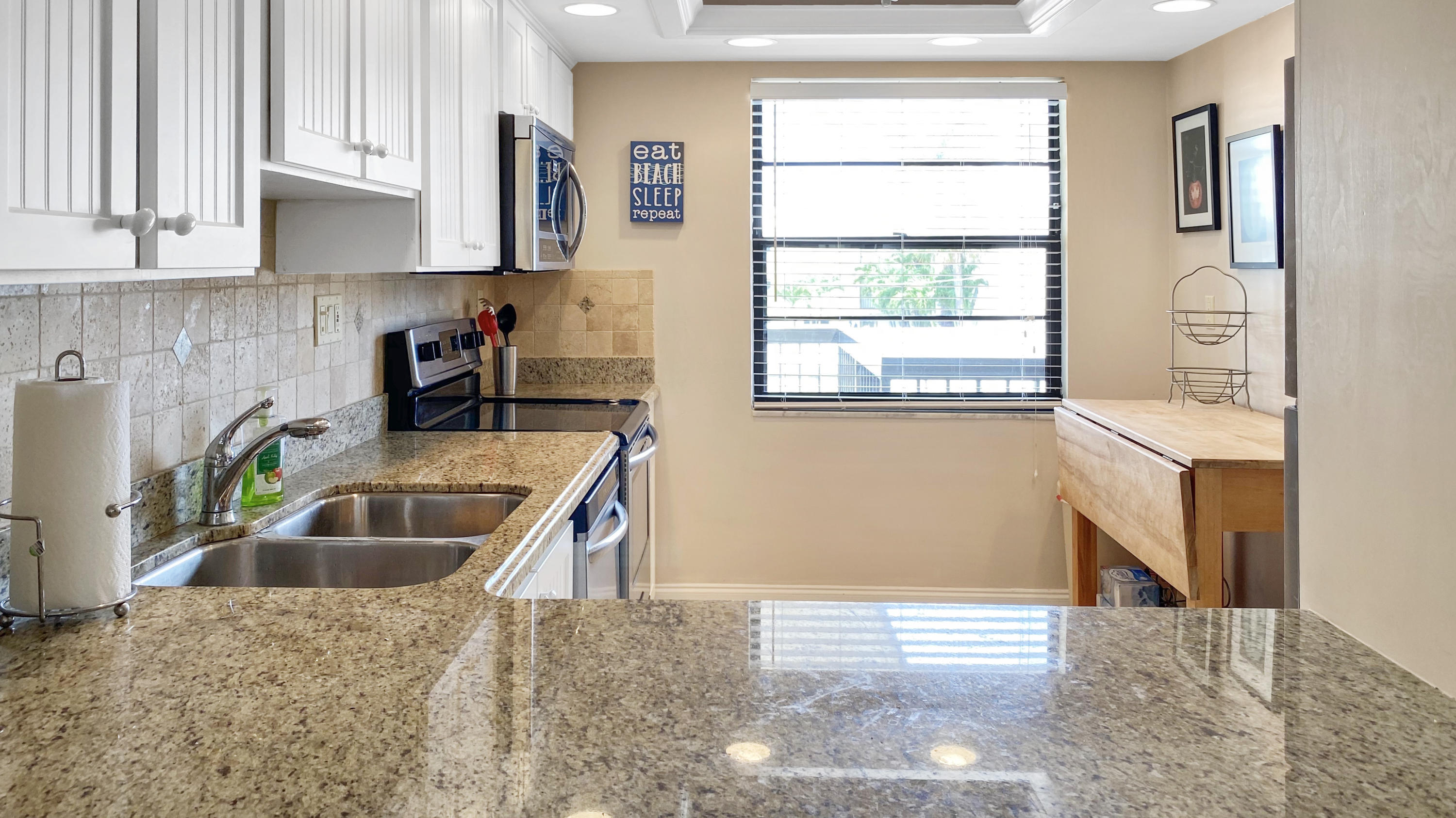 275 South Beach Road, Unit B202 Jupiter, FL 33469 - Photo 8 of 25 a kitchen with granite countertop a sink and a stove top oven