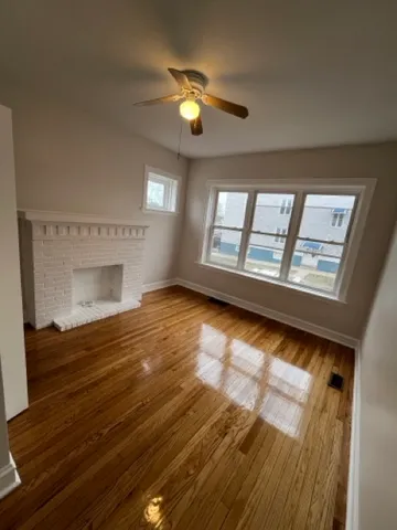 a view of an empty room with a window and wooden floor