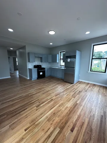 a large room with stainless steel appliances granite countertop a dishwasher and a wooden floors