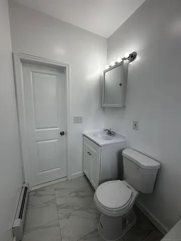 a bathroom with a granite countertop toilet a sink and mirror