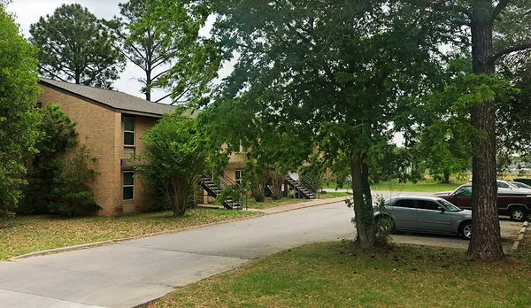 a view of a car parked in front of a house with a large tree