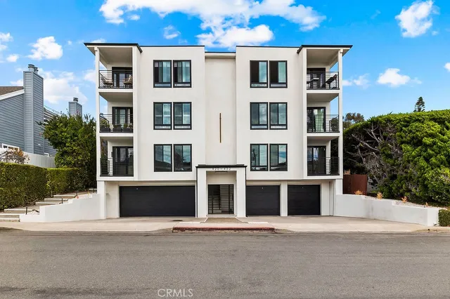 an aerial view of a city with lots of residential buildings and ocean view in back