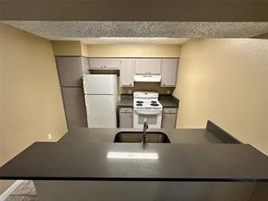 4607 East 12th Street, Unit 1 Austin, TX 78721 - Photo 3 of 9 Kitchen with dark countertops, a peninsula, white appliances, and range hood