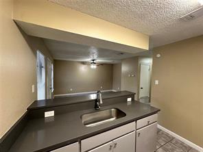 4607 East 12th Street, Unit 1 Austin, TX 78721 - Photo 5 of 9 Kitchen featuring dark countertops, white cabinets, ceiling fan, light tile patterned floors, and a textured ceiling
