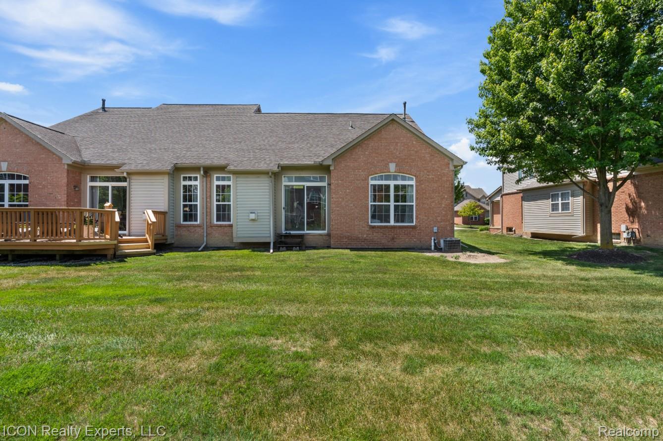 531 Cherry Grove Road Canton, MI 48188 - Photo 27 of 30 Expansive backyard featuring a wood deck, red brick exterior, light-colored siding, multiple windows, and a mature tree