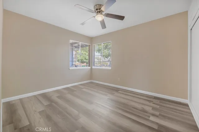 an empty room with wooden floor and windows