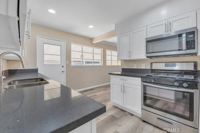 a kitchen with stainless steel appliances granite countertop a stove a sink and a microwave