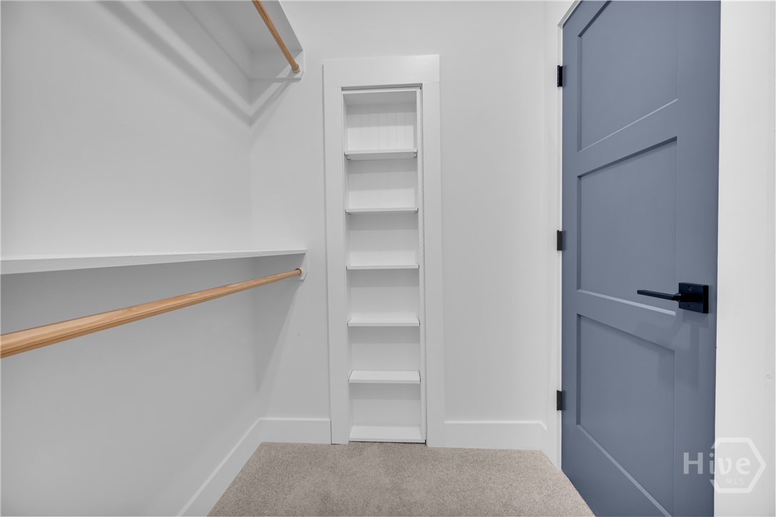 2476 St Martin Way Monroe, GA 30656 - Photo 46 of 75 Walk-in closet featuring built-in shelving, two hanging rods, and a plush carpeted floor