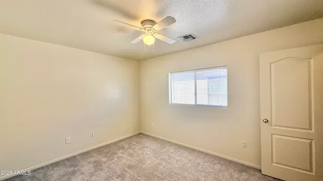 an empty room with a window and ceiling fan