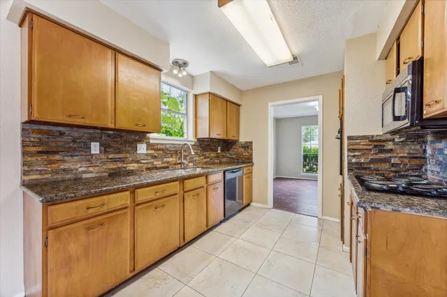 a kitchen with stainless steel appliances granite countertop a stove a sink and a microwave