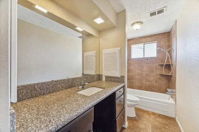 a bathroom with a granite countertop sink a toilet and bathtub