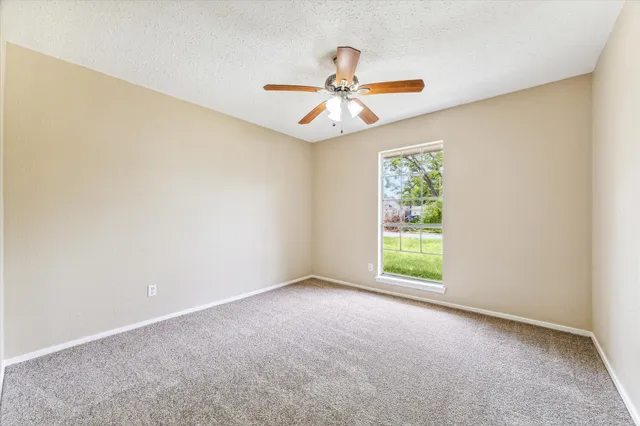 an empty room with windows and fan