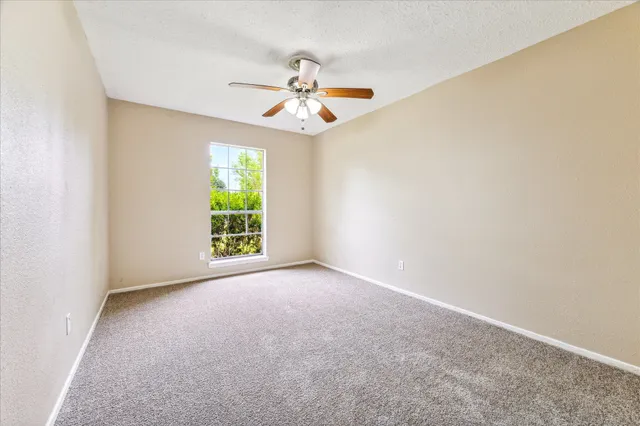 an empty room with windows and fan