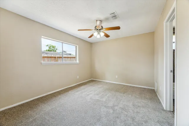 an empty room with windows and ceiling fan