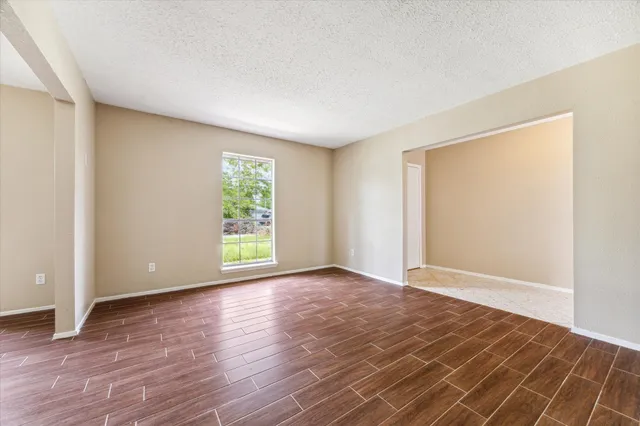 a view of an empty room with wooden floor and a window
