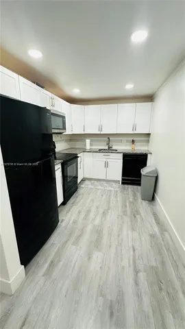 a kitchen with stainless steel appliances kitchen island granite countertop a refrigerator a sink and a stove top oven