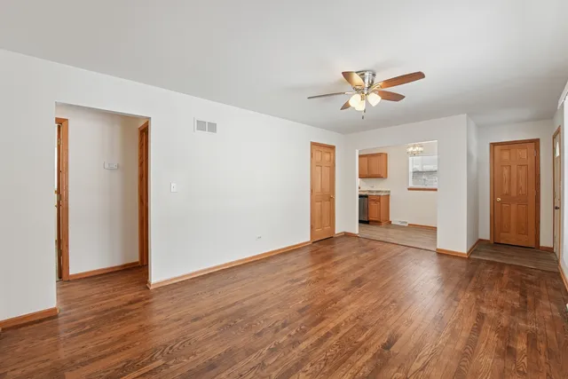 a view of empty room with wooden floor and ceiling fan