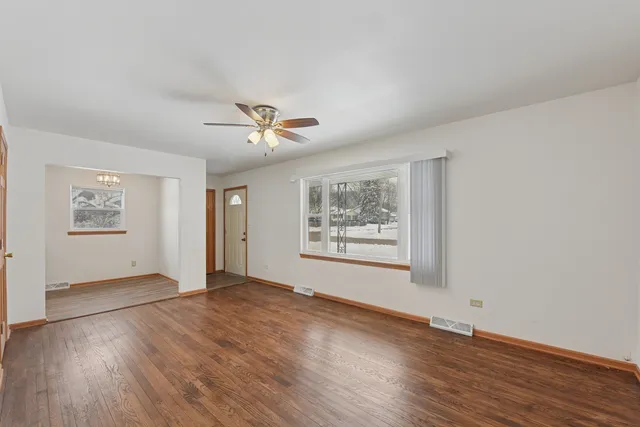a view of an empty room with a window and wooden floor